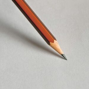 Detailed close-up of a wooden pencil resting on white paper, perfect for educational themes.