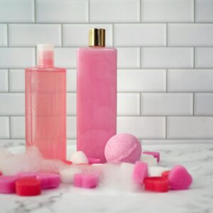 Elegant display of pink bath products on a marble surface with a tiled backdrop.