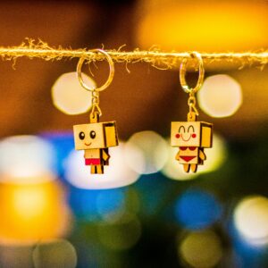 Colorful cartoon keychains hanging on a string with a vibrant bokeh background.