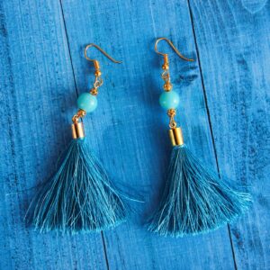 Stylish blue tassel earrings with gold accents displayed on a wooden surface.