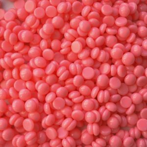 Close-up of pink wax beads used in cosmetic depilation and hair removal treatments.