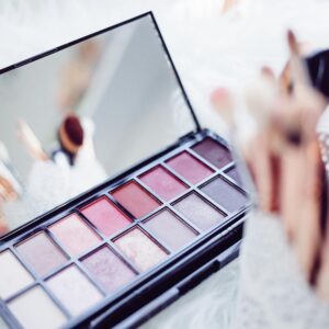 Close-up of a makeup palette and brushes reflecting in a mirror, emphasizing beauty and fashion.