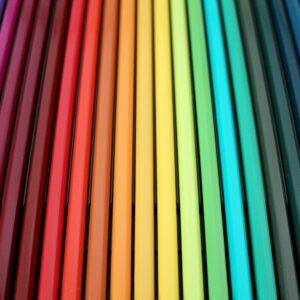 A vibrant and colorful arrangement of colored pencils forming a rainbow spectrum pattern.