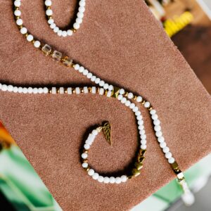 Close-up of a stylish beaded necklace with gold accents on a brown textured base.