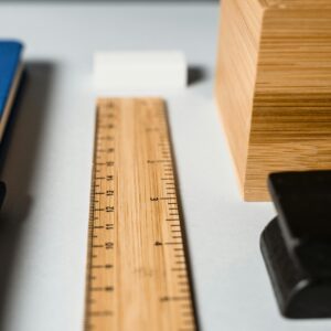Close-up of a wooden ruler with desk stationery, highlighting measurement and office workspace.
