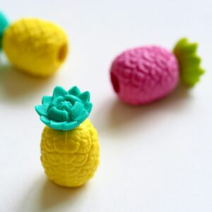 Bright and colorful pineapple-shaped rubber erasers on a light surface.