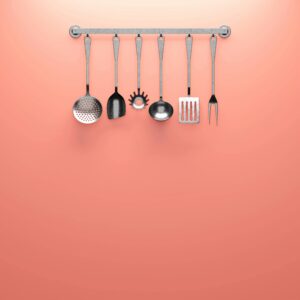 Hanging kitchen utensils against a coral backdrop, ideal for minimalistic design concepts.