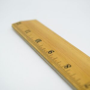 A wooden ruler with numbered markings on a plain white background.