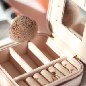 A luxurious jewelry box with earrings and a makeup brush bathed in gentle sunlight.