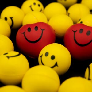 Bright collection of yellow and red smiley face balls and hearts on a dark background.