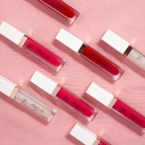 pexels-photo-15854300-15854300 Flat lay of colorful lip glosses on a soft pink fabric background.